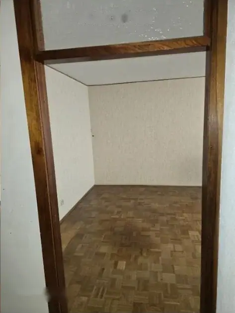 Leergeräumtes Wohnzimmer mit freigelegtem Parkettboden