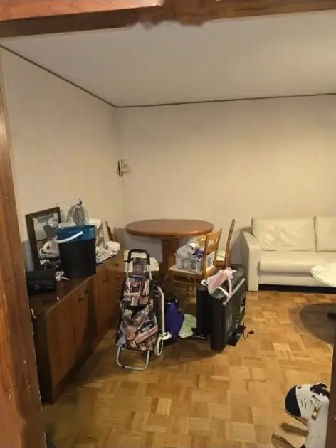 Wohnzimmer mit Esstisch, Sofa und gestapelten Kartons