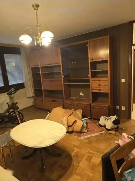 Wohnzimmer mit raumhoher Schrankwand, Esstisch und Luster