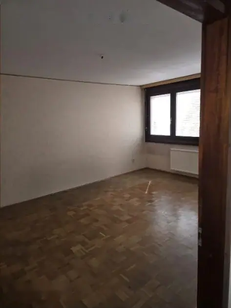 Leeres Wohnzimmer mit Parkettboden und Fenster
