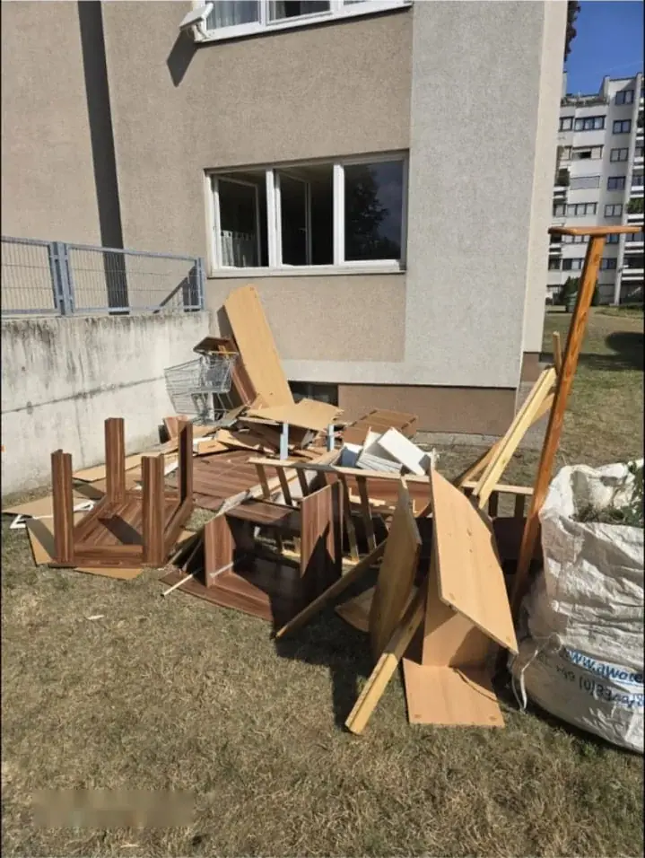 Zerlegte Möbel und Sperrmüll auf der Wiese vor einem Wohnhaus